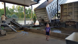 Child at facility with trucks unloading vegetables.