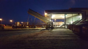 Nighttime truck unloading at an illuminated industrial facility.