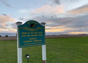 Sign for Michigan Centennial Farm, sunset in background.