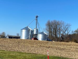 Grain silos in a harvested field under clear sky.